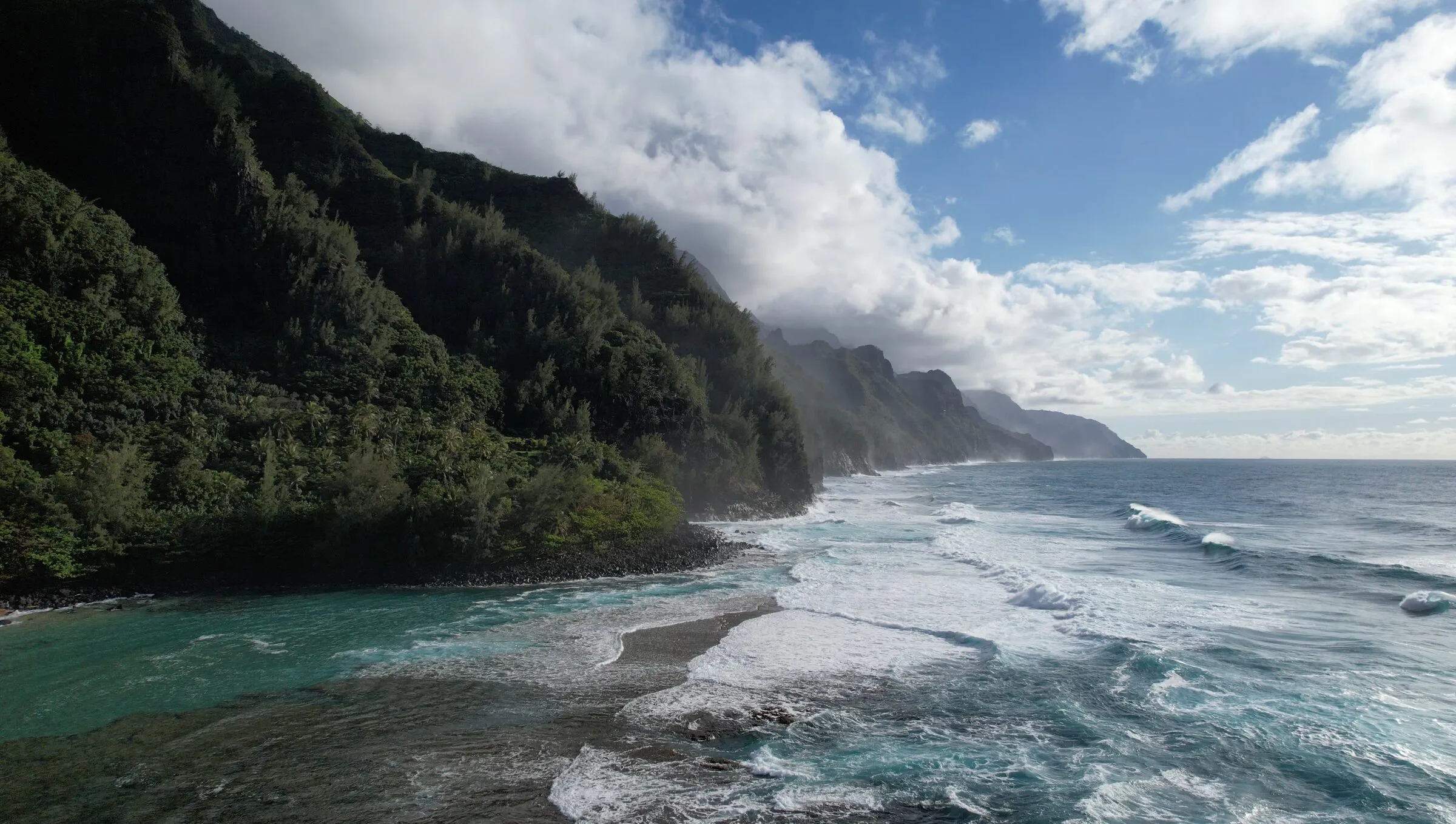 The steep green cliffs and Pacific shoreline of Kauaʻi’s Nā Pali Coast